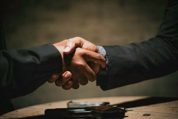 Two people shaking hands over a business deal