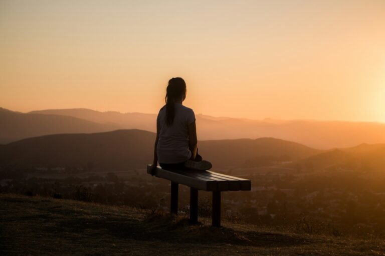 Person sitting calmly, watching a peaceful sunrise